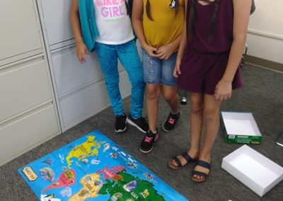 Three girls standing in front of a map.