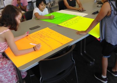 A group of people sitting at tables with papers on them.