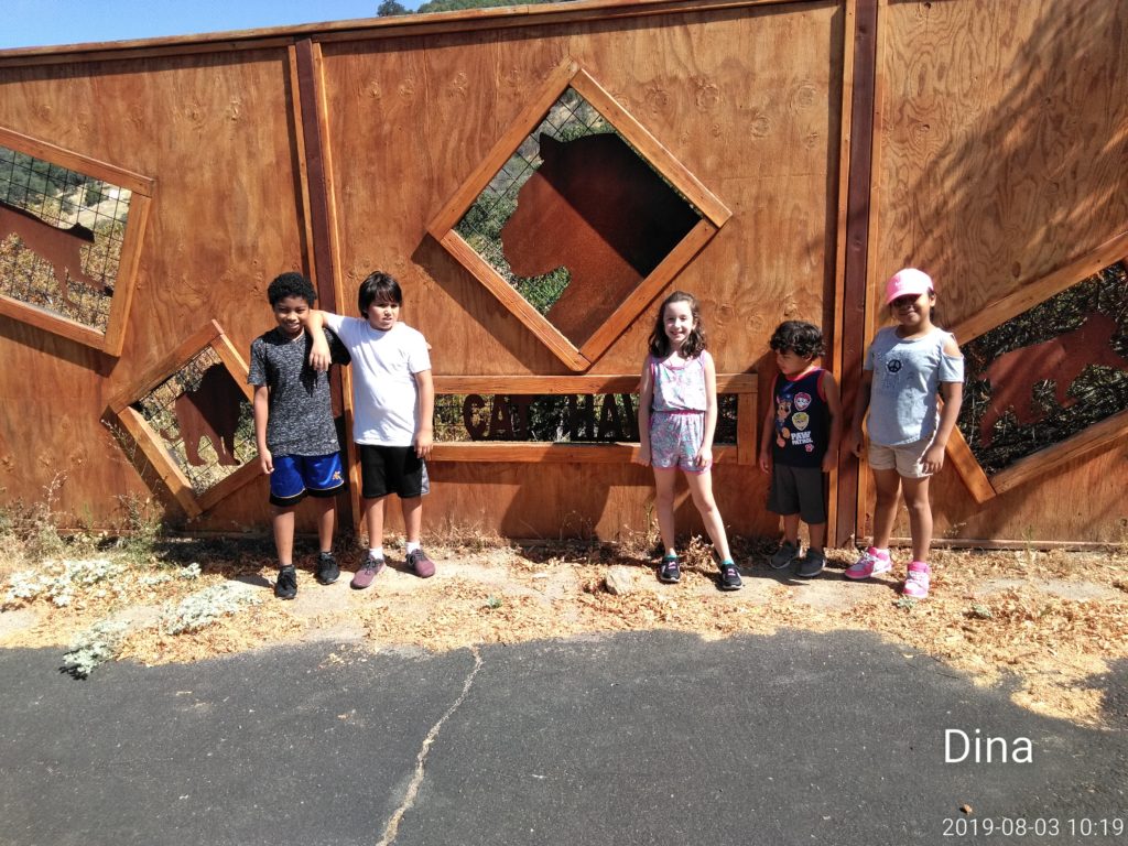 A group of kids standing next to a wooden wall.