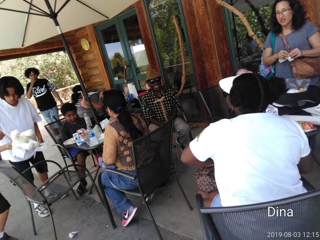 A group of people sitting at tables outside.